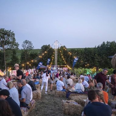 Sommerabend im Weingarten mit Lichterketten und Publikum