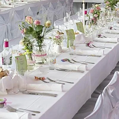 Feierlich eingedeckte Tische mit Stuhlhussen und eleganter Tischdeko